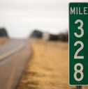 A green mile marker on an empty road.