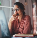 businesswoman thinking about something while sitting in front of laptop