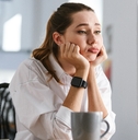 bored young woman dressed in shirt sitting at her workplace