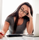 worried woman doing calculation in front of a laptop