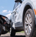 Two cars in a collision. One car is severely dented along the side. 