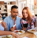happy friends with money paying bill at restaurant