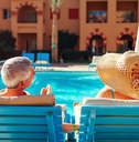 senior couple relaxing on chaise lounges besides a pool