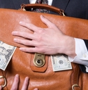 man holding briefcase with money spilling out