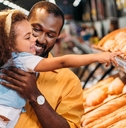little child pointing by finger at pastry to father in supermarket