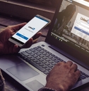 man using linkedin on smartphone and laptop