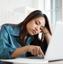 bored young asian woman typing laptop in office