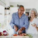 happy senior couple chopping vegetables in kitchen