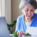 senior lady reading document and working on laptop