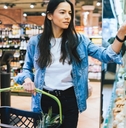 young woman holding grocery basket in a store while picking grocery