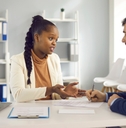 african american woman in a suit talking to a businessman writing notes in office