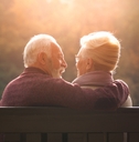 senior couple sitting on bench in autumn park