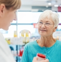 senior woman in pharmacy talking to the pharmacist