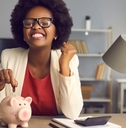 african american woman putting coins in piggy bank