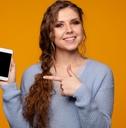 smiling young woman wearing grey sweatshirt holding smartphone