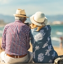 elderly couple sitting on the wall facing the beach