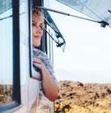 Woman smiling with head and arm over open RV window