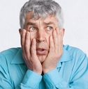 frustrated grey haired male, keeps hands on cheeks