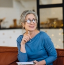 senior woman in glasses thinking and writes in a diary home