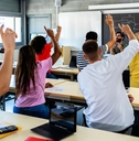 high school students raising hands in classroom