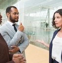 man and women standing at outdoor glass wall talking to each other