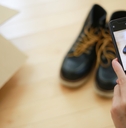 An adult capturing a photo of a pair of shoes using their phone