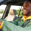 smiling african american man driving car while wearing seatbelt during day time