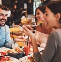 group of happy friends eating food at a restaurant