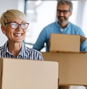 senior couple happily moving into house holding moving boxes