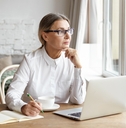 mature female writer sitting at desk at home placing chin on her hands