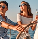 happy couple wearing shades while holding glass of champagne partying on yacht