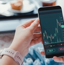 business woman sitting on couch checking stock graphs on smartphone