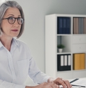 stylish senior lady with bob cut sitting on chair working at office on desktop