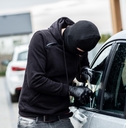 car thief trying to break into a car with a screwdriver