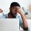 male employee having headache after working on laptop