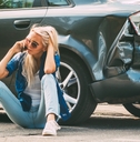 woman sits on the road near the broken car