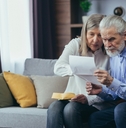 senior husband showing banking paper to confused elderly wife