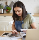 young beautiful woman working on calculator sitting on chair with laptop and papers on table