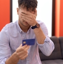 man holding credit card with worried expression 