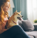 A happy woman with a dog she&#x27;s pet sitting while house sitting