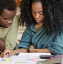 african american couple sitting on table in front of laptop reviewing documents