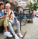 happy senior couple tourists sitting on stairs