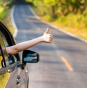 A driver on a two-lane road gives a thumbs up.