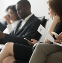 multi ethnic applicants waiting for their call using smartphones and holding papers
