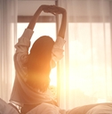 woman stretching hands in bed