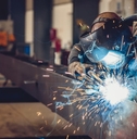 male worker using torch to weld metal at work