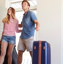 happy young couple with suitcases moving into new house