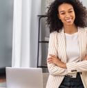 office worker stands with crossed arms near a desk