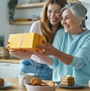 surprised senior mother receiving a gift box from her daughter