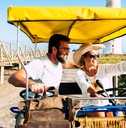 happy adult couple on a surrey bike enjoying the outdoor